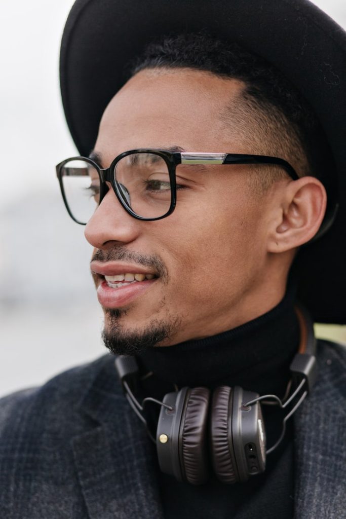 IVision Optical Ethiopia | close up portrait refined young man with brown skin photo dreamy african male model glasses headphones chilling outdoor 197531 21844
