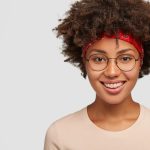 IVision Optical Ethiopia | headshot happy hipster girl with afro haircut satisfied facial expression has delighted kind smile has nostalgia gazes directly stands against white wall free space your text 273609 29116